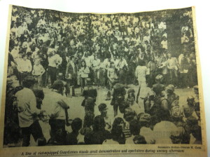 "A line of riot-equipped Guardsmen stands amid demonstrators and spectators during uneasy afternoon."